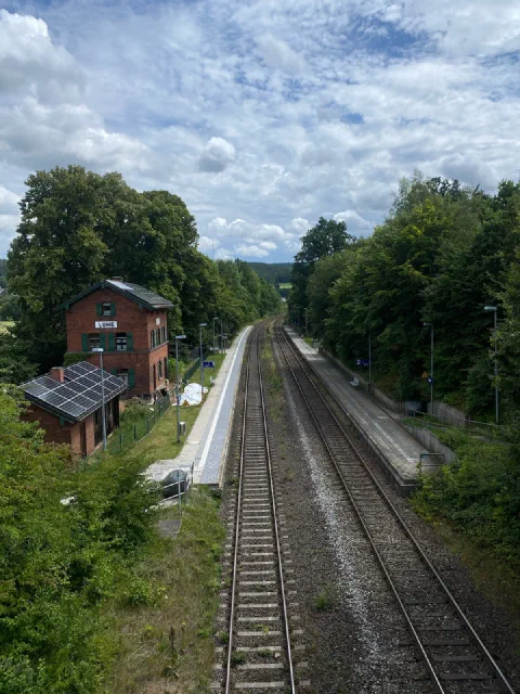 Disused railway station seen from a bridge, two tracks running into the distance