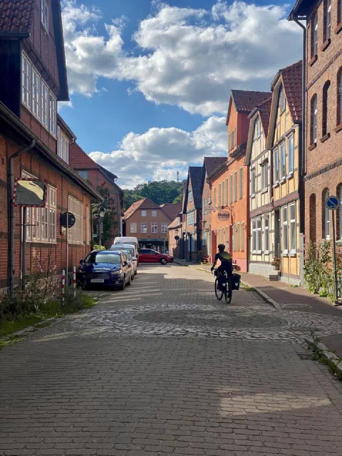 Rider in a brick street lined with half-timbered houses in the afternoon sun