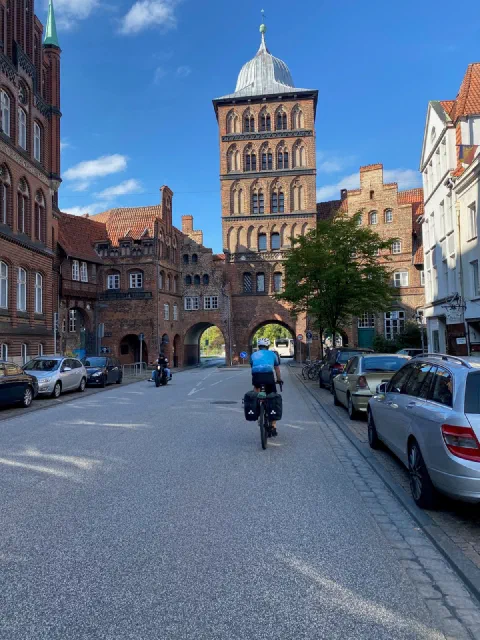 Rider approaching the Burgtor in Lübeck, red brick towers under a blue sky
