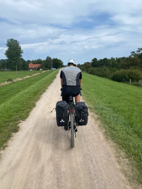 Rider on a pale gravel path along a dike between mown green banks