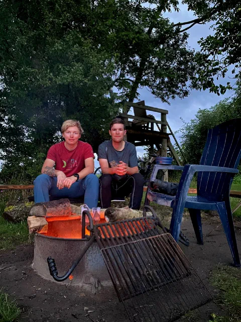 Both riders sitting by a fire with garden chairs in the evening