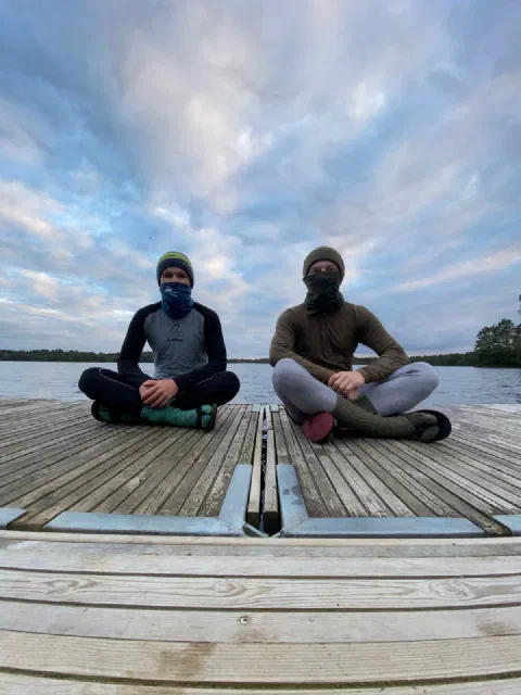 Both riders sitting cross-legged on a jetty under a big sky