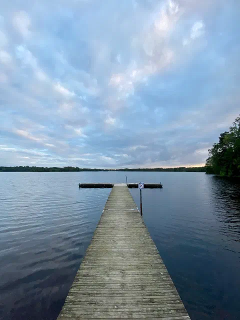 Empty jetty leading into a still lake under a streaky evening sky