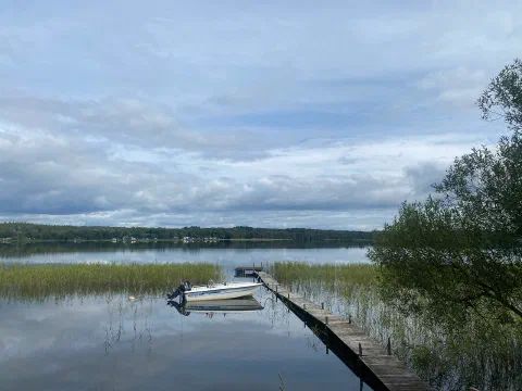 Small boat beside a jetty on a still lake, reeds and reflections