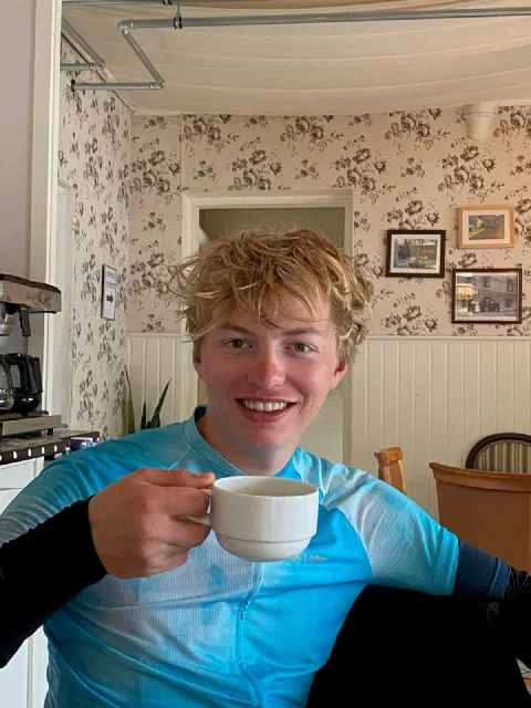 Smiling rider with a coffee cup in a Swedish kitchen with floral wallpaper