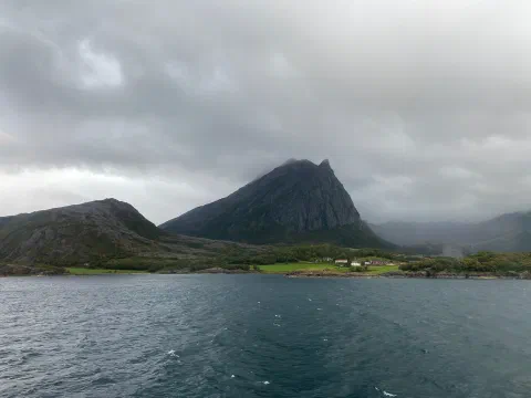 Dark pyramid-shaped peak above the choppy fjord, seen from the ferry