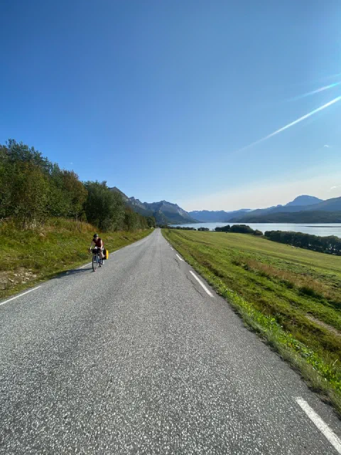 Rider far ahead on a straight road along the fjord