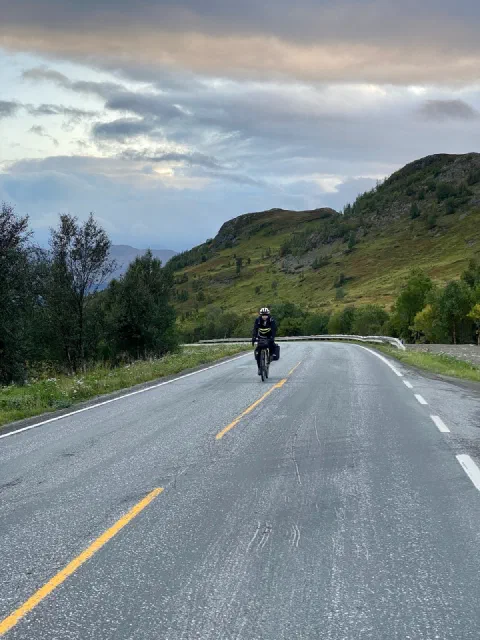 Rider approaching in golden evening light on a road between green hills