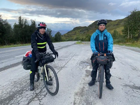 Both riders posing with their loaded bikes on a wide road, smiling
