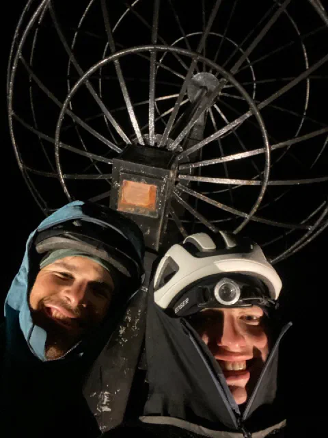 Night selfie of both riders in hoods under the Nordkapp globe: arrived