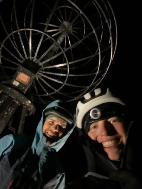 Night selfie of both riders laughing under the Nordkapp globe