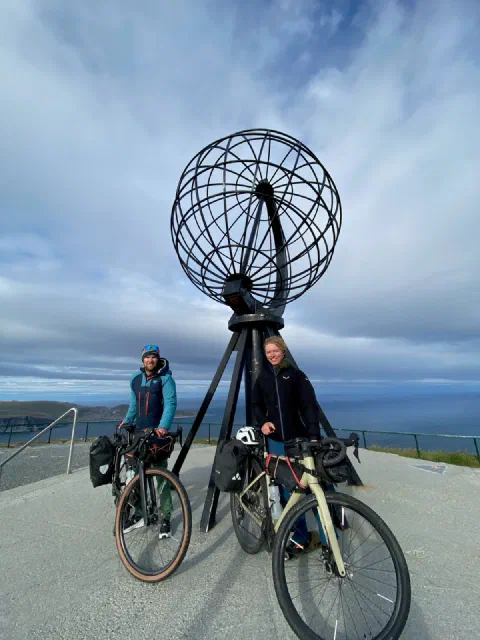 The Nordkapp globe above both riders, the sea horizon behind