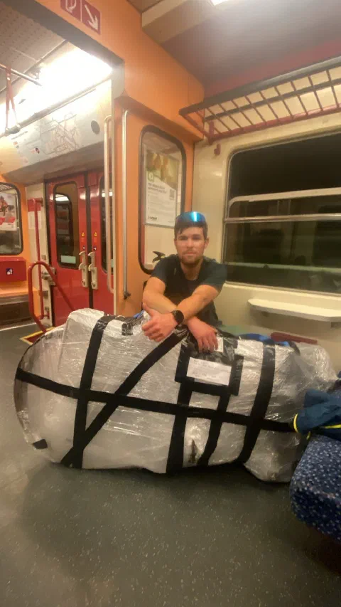 Rider sitting by the foil-wrapped bike box on an orange train, on the way home